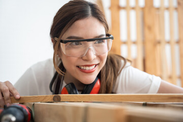 Happy female carpenter working at workshop. She preparing to design her furniture.