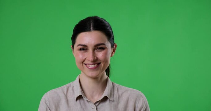 Woman standing on a green screen background, laughing and smiling joyfully at the camera. Her positive and carefree expression is contagious, conveying a sense of excitement and satisfaction.