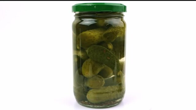 Jar with pickled cucumbers or gherkins on white closeup