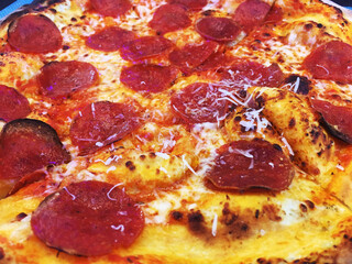 Wood fired pizza with cheese and pepperoni, whole pizza pie. Junk food, caloric pizza, top down view of a pepperoni pizza. Close up of greasy pepperoni pie. Greasy pepperoni and cheese pizza.
