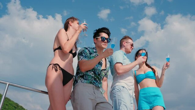 Group of young diverse people drinking wine and champagne while having sail boat party. Group of men and women friends enjoy party, having fun and talking together while catamaran boat sailing