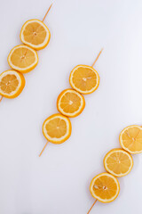 Citrus slices on a wooden skewer. Top view with lemon theme on white background.