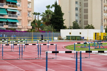 Synthetic running track for sporting events with hurdles