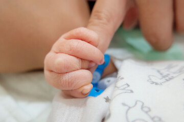 newborn's hand holds mom's finger