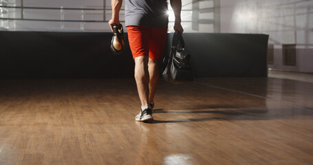 An athlete walking into a gym with a bag and boxing gloves, ready to start training - sports,...
