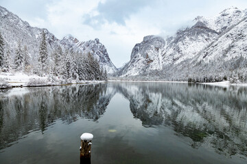 Beautiful view of Dobbiaco Lake (Toblacher See) on a snowy winter day, with reflections of mountains in the Dolomites, Bolzano, Italy