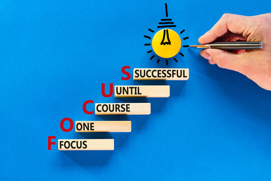 FOCUS follow one course until successful symbol. Concept words FOCUS follow one course until successful on wood block. Blue background. Business FOCUS follow one course until successful concept.