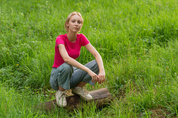 girl teenager squatting on a log in a meadow