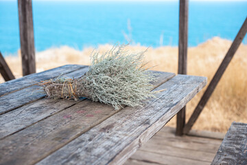 Bouquet of fragrant wormwood on a wooden table by the sea. Outdoor recreation on a warm autumn day