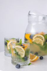 lemonade in a glass and a jug on a white background. Summer refreshing drink. Cold detox water with lemon