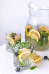 lemonade in a glass and a jug on a white background. Summer refreshing drink. Cold detox water with lemon