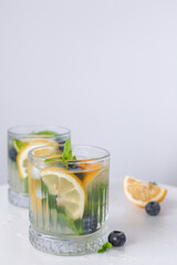 lemonade in a glass and lemons on a white background. Summer refreshing drink. Cold detox water with lemon