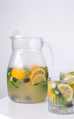 lemonade in a glass and a jug on a white background. Summer refreshing drink. Cold detox water with lemon