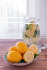 lemonade in glass and jug on wooden table outdoors. Summer refreshing drink. Cold detox water with lemon