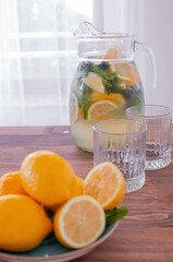 lemonade in glass and jug on wooden table outdoors. Summer refreshing drink. Cold detox water with lemon