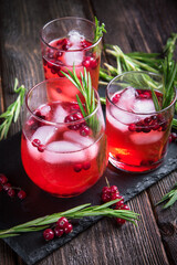 Glasses of currant juice on a black stone board and a wooden table.