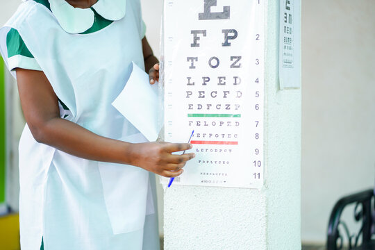 cropped image of african nurse with eye test chart- health concept