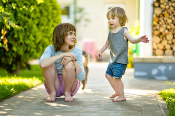Cute big sister cuddling with her toddler brother. Adorable teenage girl holding baby boy. Children with large age gap.