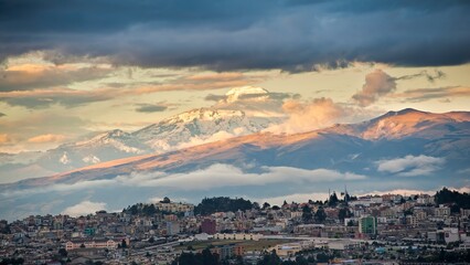 The Cayambe volcano dominating the city of Quito and illuminated by the evening sun with a stormy cloudy sky
