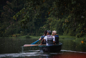 Male and female tourists enjoying rowboat tour exploring along the Tortuguero canal and forest in...