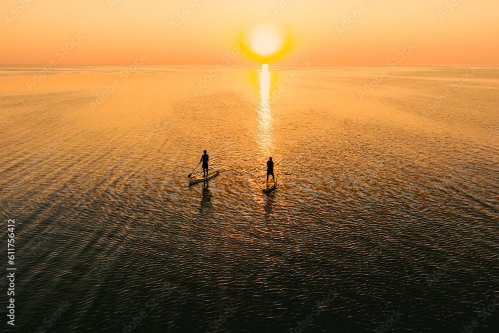 Canvas Prints aerial view of two people on stand up paddle boards on quiet sea at sunset. warm summer beach vacati - Canvas Prints