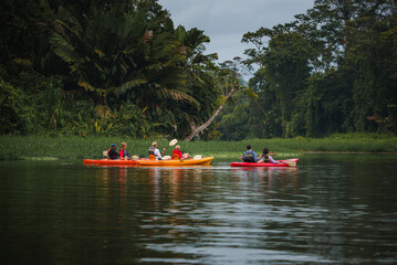 Male and female tourists enjoying rowboat tour exploring along the Tortuguero canal and forest in...