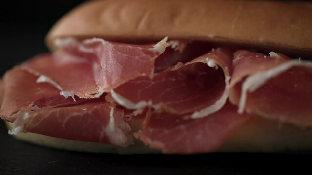 sandwich with sliced spanish iberico ham on black wooden board