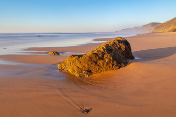 Fototapeta na wymiar Sunset over beach (Castelejo Beach, Praia do Castelejo) with rock at the atlantic southwest coast of Portugal 