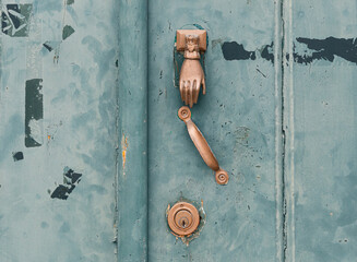 Close up of traditional knocker in the shape of a hand on an green painted door in the medieval city of Mertola, Algarve Portugal
