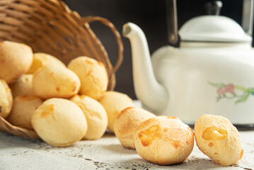 Cheese bread, Basket with cheese bread lying on a white lace tablecloth and accessories, dark background, selective focus.