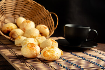 Cheese bread, Basket with cheese bread lying on a wooden woven mat and accessories, dark background, selective focus.