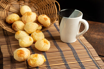 Cheese bread, Basket with cheese bread lying on a wooden woven mat and accessories, dark background, selective focus.