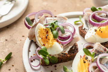 Smorrebrod sandwiches with herring fillet, rye bread, cream cheese, boiled egg slices, onion rings...