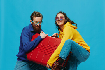 Obraz premium Woman and man smile suitcases in hand with yellow and red suitcase smile fun, on blue background, packing for a trip, family vacation trip.
