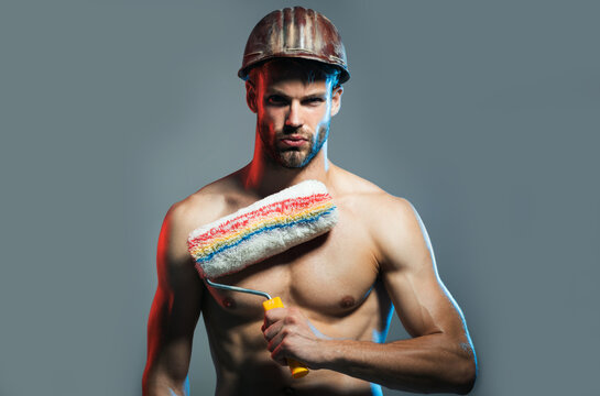 Painter man with paint roller. Strong builder worker painter decorator in hardhat. Sexy guy in safety helmet with paint roller. Muscular shirtless painter man with painting tool. Room painting job.
