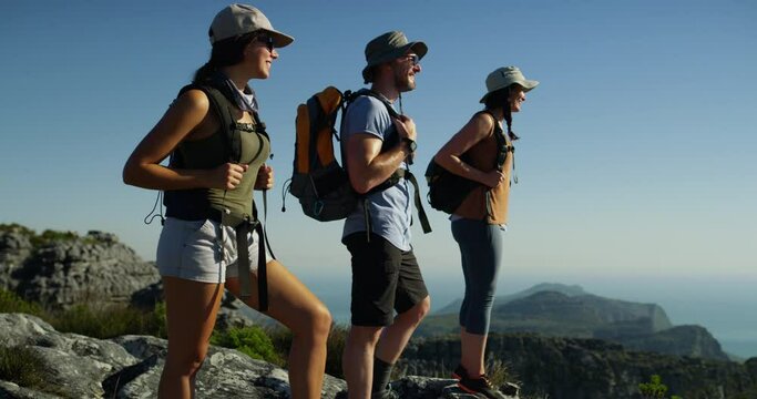 Fitness, freedom and hiking friends on a mountain happy, smile and bonding on blue sky background. Hike, exercise and group of people on hill top for travel, workout or backpacking in nature together
