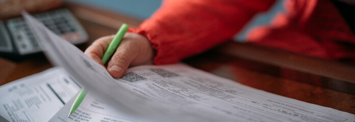 The hands of an elderly woman with a calculator and a lot of utility bills. Pensioner and payment of utilities for heating