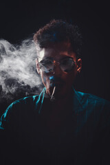 Black Young Man with Glasses Smoking Cigar with Fog at Black Background
