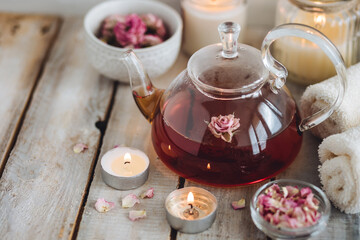Concept of natural organic flower, herbal ingredients for spa treatment for relaxation and detox. Hot tea with rose extract, petals for beauty procedures, towel, candles for detention and meditation