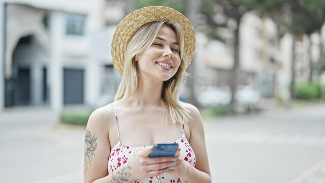Young blonde woman tourist smiling confident using smartphone at street