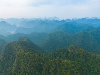 Aerial top view of forest trees and green mountain hills with fog, mist and clouds. Nature landscape background, Vietnam.