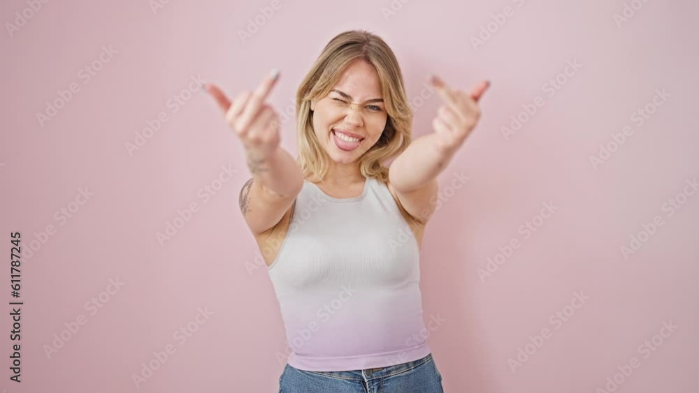 Poster young blonde woman smiling confident doing middle finger gesture over isolated pink background