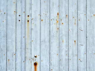 Closeup of vertical weathered  boards with rusted nails. Background of a light blue wooden surface