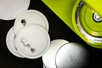Pin button making green machine over a black background. Blank badges on the frame.