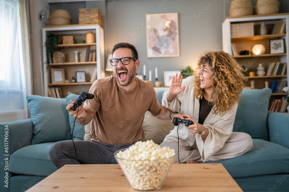 Wall mural couple man and woman husband wife play console video games at home