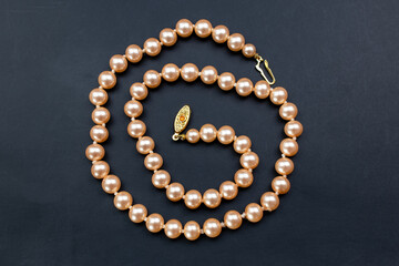 Unique retro pearl necklace on black background, vintage jewelry concept, promotional photo for an online jewelry store