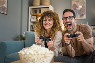 couple man and woman husband wife play console video games at home