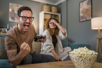 couple man and woman husband wife play console video games at home