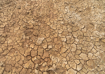 Dry ground rough cracks in the land with sand in paddy rice field. serious water shortages and Drought barren arid pattern texture background.