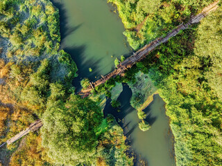Aerial view of rural wooden bridge over small forest river.